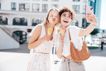 Two young beautiful smiling hipster female in trendy summer clothes. Carefree women posing on...