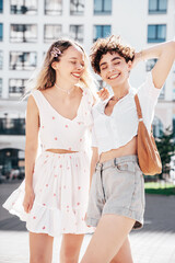 Two young beautiful smiling hipster female in trendy summer white t-shirt and shorts clothes. Sexy...