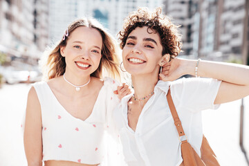 Two young beautiful smiling hipster female in trendy summer white t-shirt and shorts clothes. Sexy...