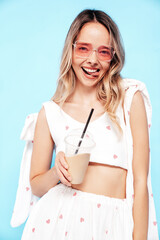 Young beautiful smiling blond female in trendy summer white clothes. Carefree woman posing near...