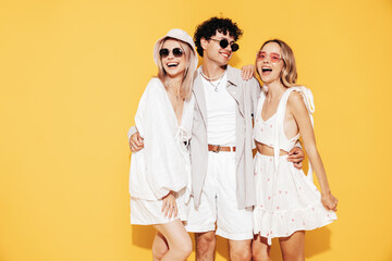 Group of young three stylish friends posing in studio. Fashion man and two cute female dressed in...