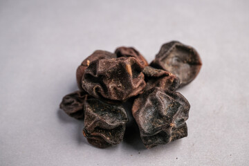 Macro Close-up of Wrinkled Dark Brown Dried Sebesten Fruit (Cordia myxa) Used in Traditional Medicine as a Demulcent and Expector