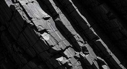 Dramatic black and white close-up of rugged rock face with strong shadows and textures.