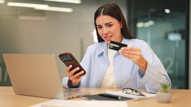 Focused woman performs online payment, using credit card and smartphone. Initial frustration with transaction gives way to determination and focus, resolving the issue in modern digital world.