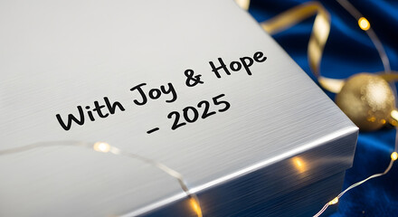 New year 2025 message on a silver gift box decorated with festive lights and ribbon