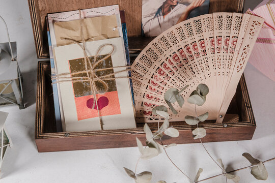 wooden keepsake memory box with old postcards and letters, tender colors, folding fan, old style, white cardboard background