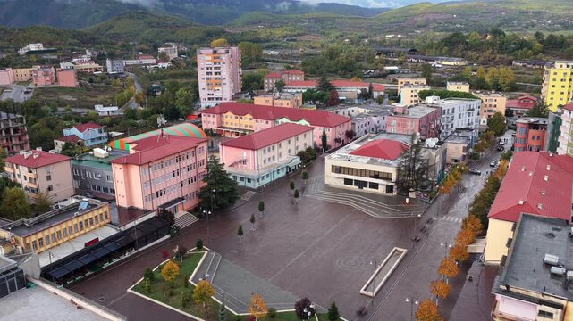 Aerial view of Abat Do&ccedil;i Square in Rr&euml;shen, Northern Albania, surrounded by colourful buildings, autumn trees and rolling hills.