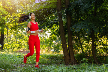 Young woman enjoys a morning jog through a sunny forest wearing bright athletic gear