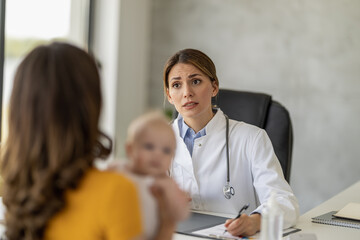 Fototapeta premium Medical consultation between a pediatrician and a mother with a baby in a modern clinic setting