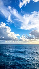 Obraz premium Aerial view of an open ocean and partly cloudy sky with patches of sunlight