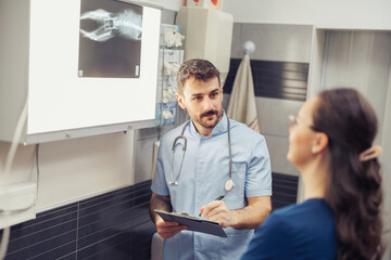 Medical professional discusses X-ray results with patient in a healthcare setting during daytime