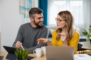 People collaborate on creative project in cozy indoor workspace with laptop and tablets during daytime