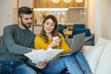 Couple reviews important documents while relaxing at home in cozy living room
