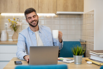 Man enjoys coffee while working on laptop in modern kitchen setting during morning hours