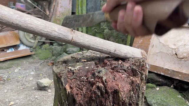 Footage of a hand using a machete to cut wood with firm, controlled movements.