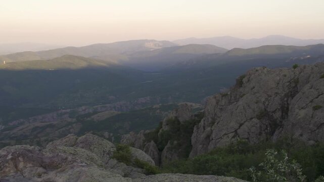 Pan shot captures a view of the Balkan Mountains and Sliven city in the early morning. The warm light spreads across the sky and landscape. Nature reveals its beauty. Stara planina in Bulgaria.