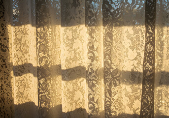 Lacy curtains illuminated by sunlight