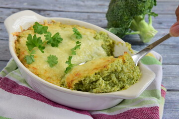 Baked broccoli with cheese on baking dish garnish with parsley