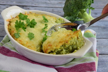 Baked broccoli with cheese on baking dish garnish with parsley