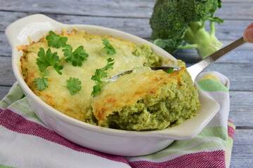 Baked broccoli with cheese on baking dish garnish with parsley