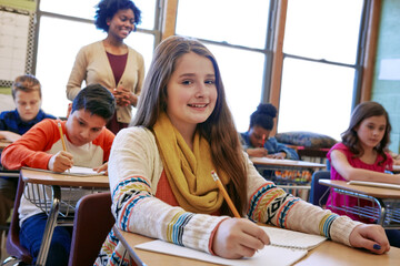 Portrait, happy girl and learning in classroom with notebook for knowledge, education or assignment. Kid, classmates or teacher in school with pencil for workbook activity, assessment or development.