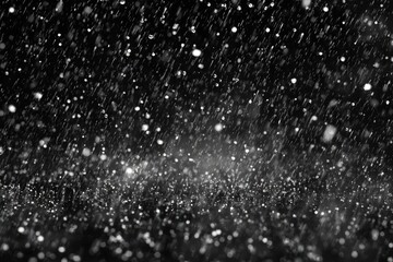 Black and white close-up captures rain or snow, with blurred droplets falling