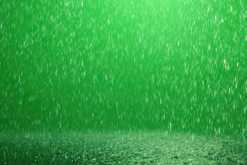 Rain showers falling from above against a bright green backdrop, creating a wet, grassy ground