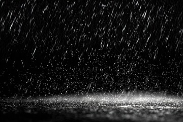 Black and white photograph captures rain falling heavily on a reflective surface