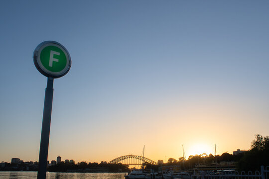 a ferry sign with sydney harbour and the bridge in the background