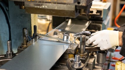 Metal stamping process with factory worker using specialized tool on press machine