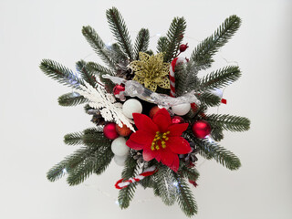 Festive holiday arrangement featuring vibrant red flowers, pine branches, and decorative ornaments, creating a cheerful atmosphere for seasonal celebrations and winter festivities