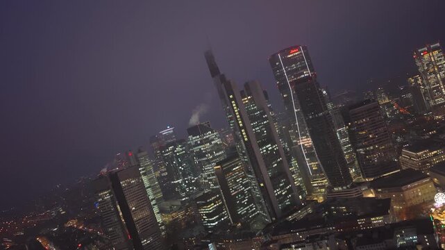 Aerial view in canted angle of Frankfurt's financial district at night. Illuminated skyscrapers of famous skyline create a stunning cityscape
