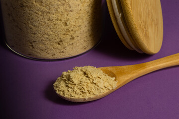 Inactive nutritional yeast flakes supplement in wooden spoon. Cheese substitute for vegan cooking