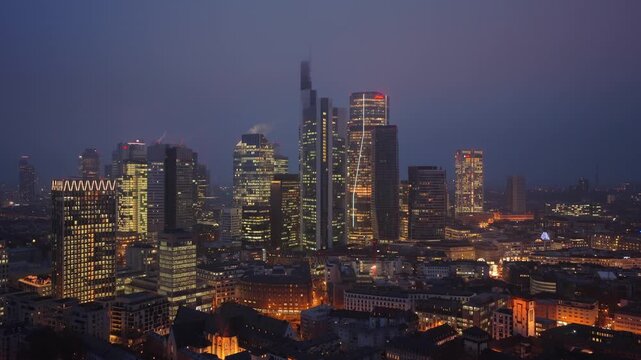 Panoramic view of Frankfurt's skyline at twilight, showcasing illuminated skyscrapers of famous financial and business district