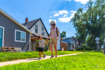 Mother and son walking on sidewalk in suburban neighborhood in drumheller, canada
