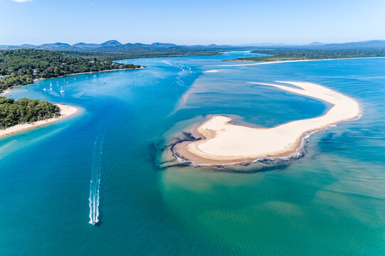 Speed boat passing sandbar in a tidal creek at Seventeen Seventy, Queensland