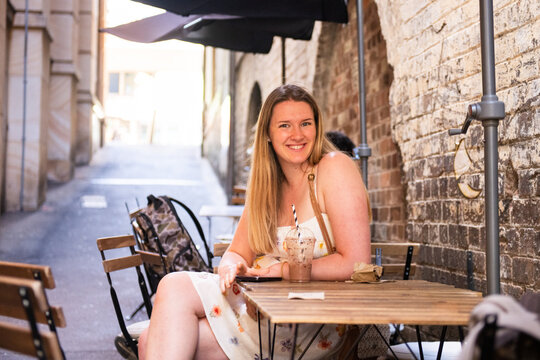 young woman sitting at a table in an alleyway cafe