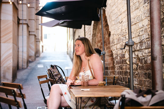 young woman sitting at a table in an alleyway cafe