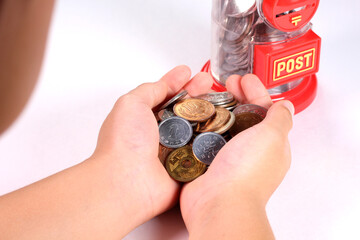 小銭を持つ子どもの手とポスト型の貯金箱