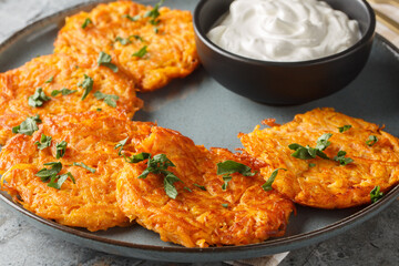 Sweet Potato Hash Browns with crispy edges and a buttery center served with sour cream closeup on the plate on the table. Horizontal