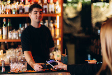 Customer Makes Contactless Payment to Bartender in Trendy Bar Setting