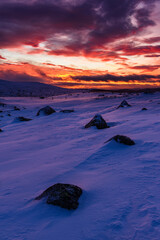 Winter scenery at sunrise in Sweden featuring snow-filled landscape and rocky formations