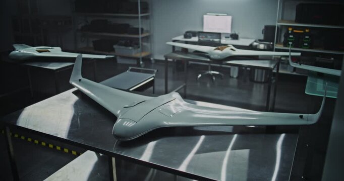 Flying Wing Design Multiple Tactical UAV on Production Tables. Several UAV Featuring Flying Wing Design Placed in Industrial Environment. Concept of Modern Aerodynamic Design and Production Readiness.
