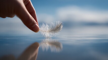 A delicate feather held by a hand over calm water, reflecting a serene and tranquil scene.