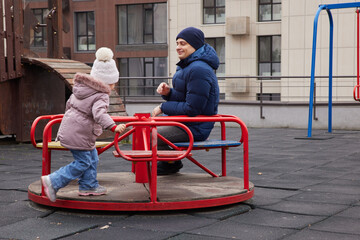 Father and daughter playing on a carousel, bonding and having fun