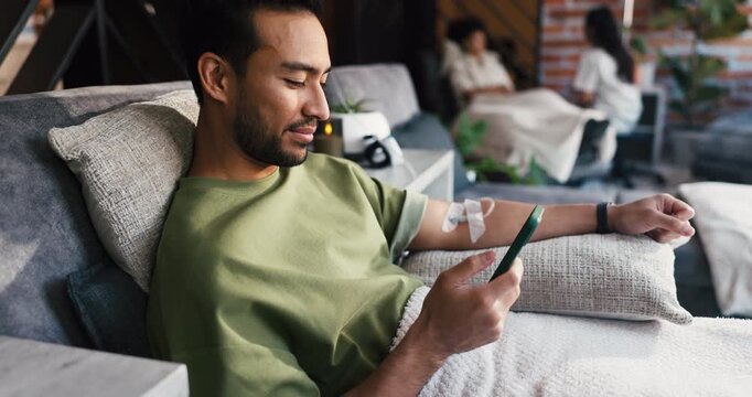 Man, phone and drip therapy in lounge, smile or social network with saline solution for immune system boost. Person, smartphone and mobile app with iv for wellness benefits, detox or mineral infusion