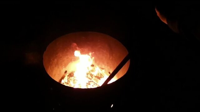 Stirring A Well Lit Fire Pit With Embers And Fire Swirling Around