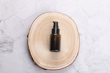 Top view horizontal of amber cosmetic bottle on natural wooden base over light geometric stone background. Minimalist style with copy space. Concept of natural skincare and wellness