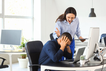 Male worker with his angry boss at desk in office