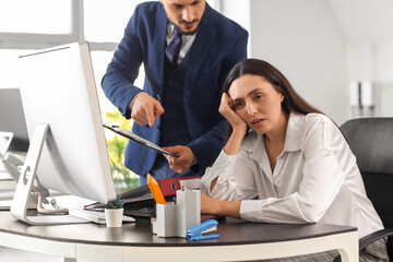 Angry male boss scolding female employee in office